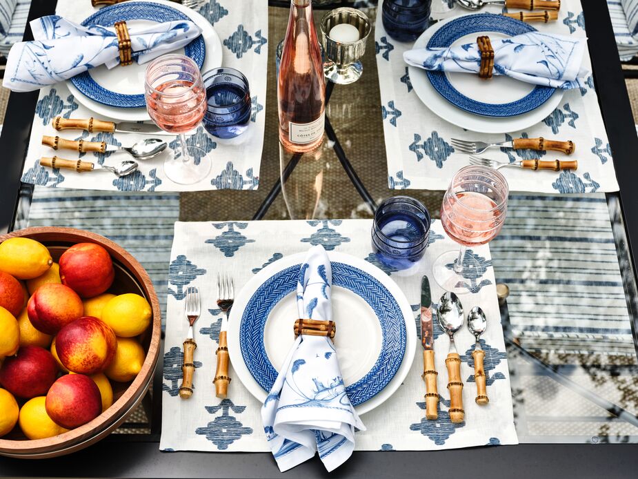 Pastels aren’t the only way to set a warm-weather table, as shown here in Nicky Hilton Rothschild’s outdoor setting. Blue-and-white also works well, especially when there’s more white than blue or the blue is a pale shade. Here, classic white dinner plates rest atop Rubia Place Mats and beneath Le Panier Salad Plates. The Bamboo Place Settings and Classic Bamboo Napkin Rings hint at tropical ease. The Isabella Acrylic Tumblers in Blue and the clear Isabella Acrylic Wineglasses add timeless elegance. Photo by Read McKendree.
