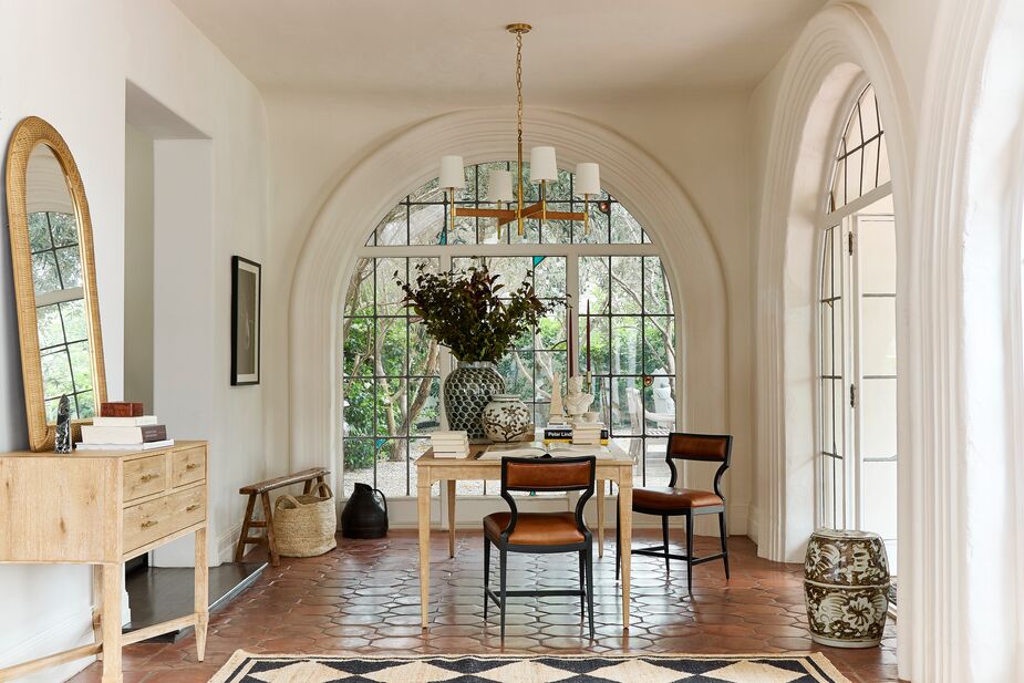 Juxtaposing curves and straight lines, leather and wood, the Raylan Leather Chairs are a medley of shapes and textures in and of themselves. Add to that the wool-and-jute Orchard Diamond Rug in Black layered on terracotta tiles, the glossy porcelain jars atop the hardwood Sarah Extension Dining Table in Limewash, and the rattan-wrapped brass of the Elle Large Rattan Chandelier, and you have a room burnished with depth and sophistication. Also shown: the Sarah Hall Chest/Console in Limewash.
