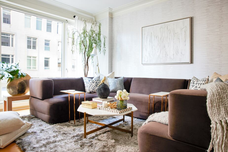 Gold and marble bring undeniable glamour to Nicole’s living room. The plush rug and plump cushions—including the Nairobi and Durban pillows, designed by Nikki for One Kings Lane—contribute cozy comfort, while the plants and the oak bench alongside the window add organic allure. Find the coffee table here. 
