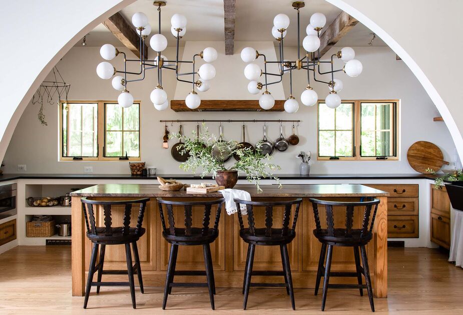 As this kitchen proves, Lauren Liess is a master of the new modern farmhouse. Here her Fable Barstools sit beneath two contemporary-cool light fixtures, which shine a figurative and literal light on the weathered ceiling beams. Find similar chandeliers here. Photo by Helen Norman.
