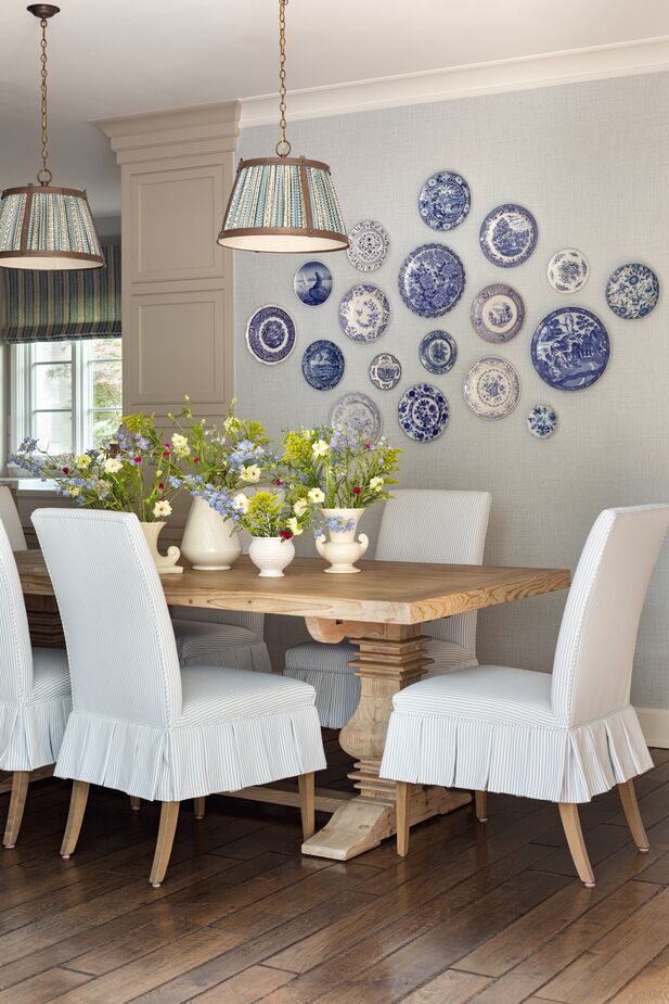 A wall in the breakfast room shows off the blue-and-white plate collection Alex’s sister has amassed over time. The pendants had belonged to their grandparents; Alex swapped out the fabric. Find a similar dining table here.
