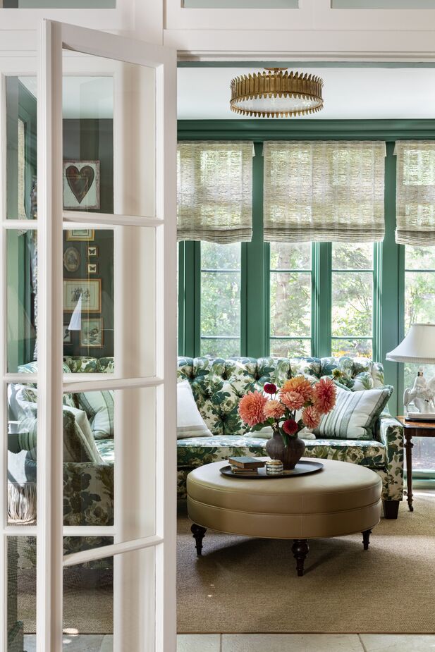 Just off the formal living room, the sunroom is a verdant jewel box. The millwork is painted the same green as the walls, adding to the cozy vibe while making the space feel larger. 
