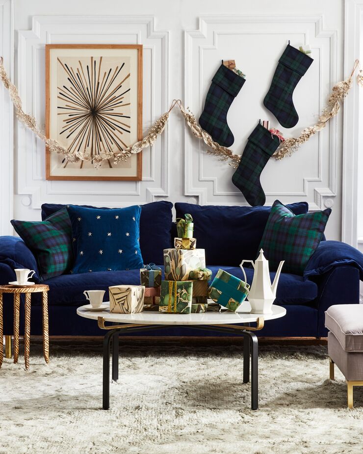 You don’t need a mantel to hang your stockings for St. Nicholas. A banister is one option, and if you don’t have a staircase, pretty much any wall will do. Find the sofa here and the velvet pillow here. Photo by Frank Frances.
