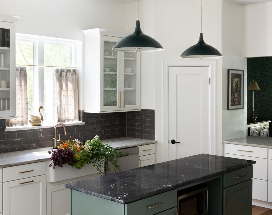 The green of the kitchen island ties in with the palette of the dining room, which is visible via a pass-through. Find similar pendants here. 
