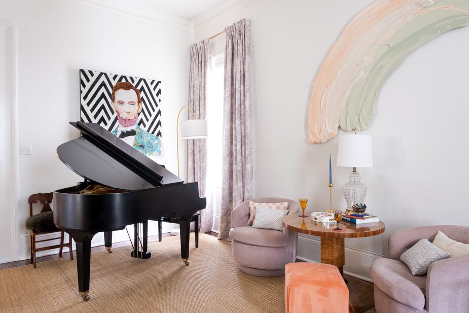 The pastel rainbow by Donald Martiny accentuates the sherbet colors of the living room’s bucket chairs and ottoman, while the black-and-white background of Ashley Longshore’s portrait of Lincoln ties in with the black piano. The neutral rug and walls ensure that the whole is greater than the sum of its parts; find a similar rug here.
