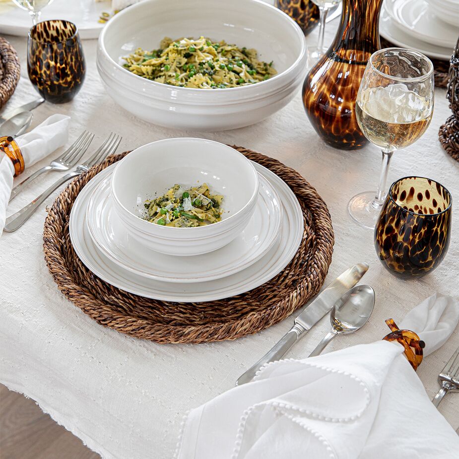 You can’t go wrong with white tableware, like the Bilboa place setting and serving bowl shown here, especially when serving colorful food. Also shown: the Rustic Rope Charger and the Berry Trim Napkin.
