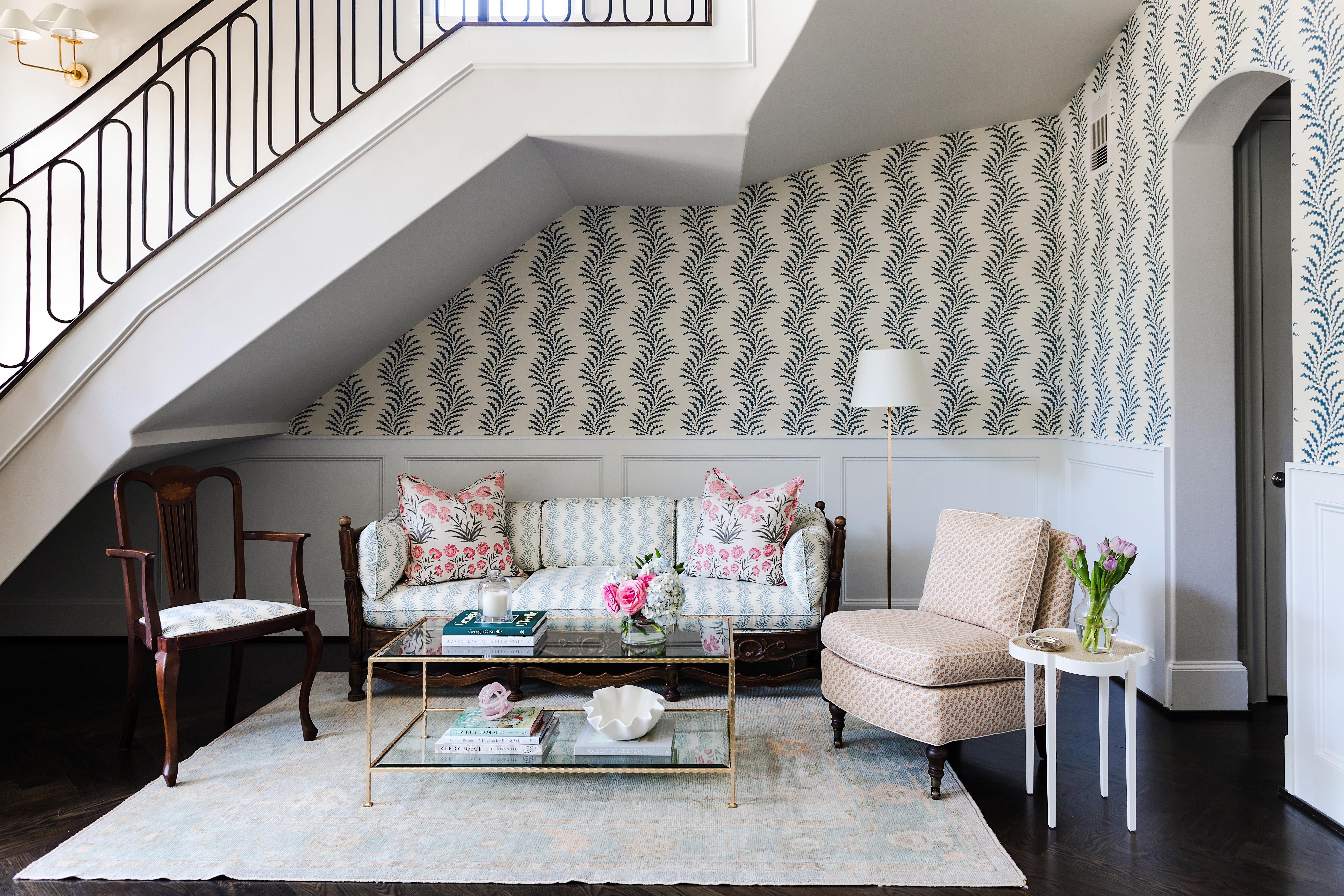 In the entry, “the wallpaper helped to give it warmth and make it feel like a singular space, even though it is three stories high,” Katie says. The pattern of the wallpaper, Scrolling Fern Frond by Soane, is repeated on the sofa and the armchair in a lighter colorway. 
