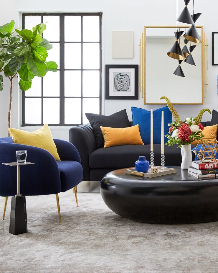 Forget what you heard about never mixing dark blue and black. The luster of the velvet chair and pillow creates chic contrast to the black sofa and table.  
