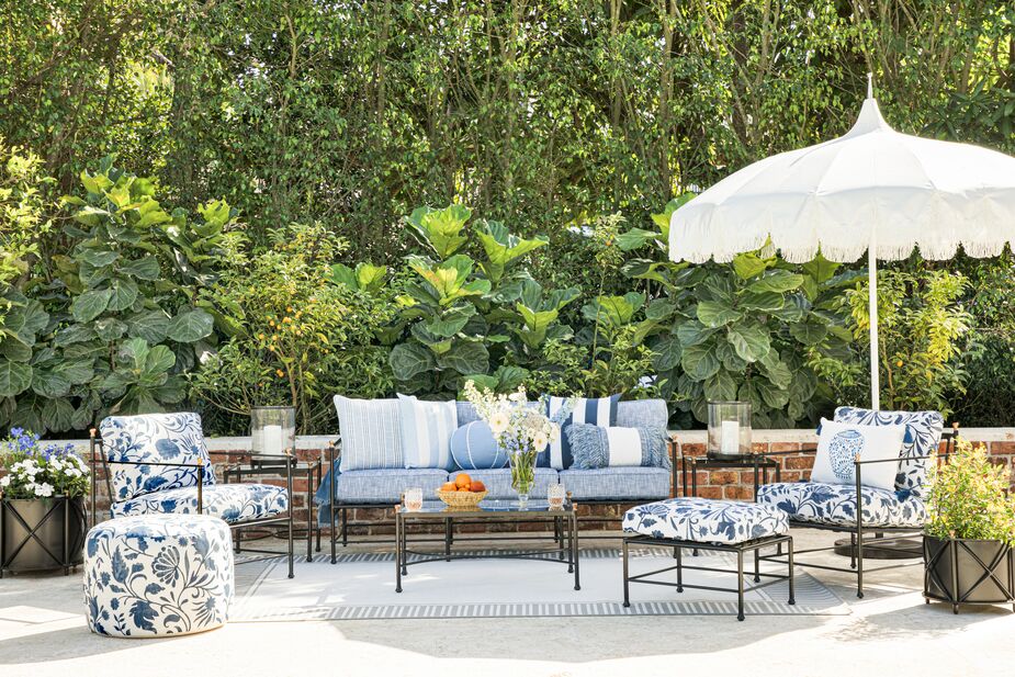Shown above: the Lola Round Pouf in Indigo Dolce Floral, the Frances Lounge Chairs in Indigo Dolce Floral, the Frances Sofa in Linen Indigo, the Frances Coffee Table in Black/Antiqued Gold, the Aya Fringe Patio Umbrella in White, and the Frances Ottoman in Indigo Dolce Floral.
