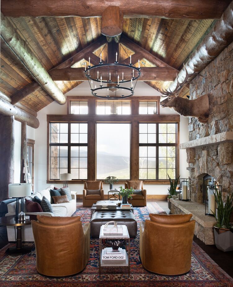 While the lantern in the entry hangs fairly low to make the space feel cozier, in the adjacent living area above the chandelier is kept high so as not to detract from the spectacular view. (Find a similar chandelier here.) The white sofa helps brighten the room even on overcast days, while the rug introduces pattern as well as color.
