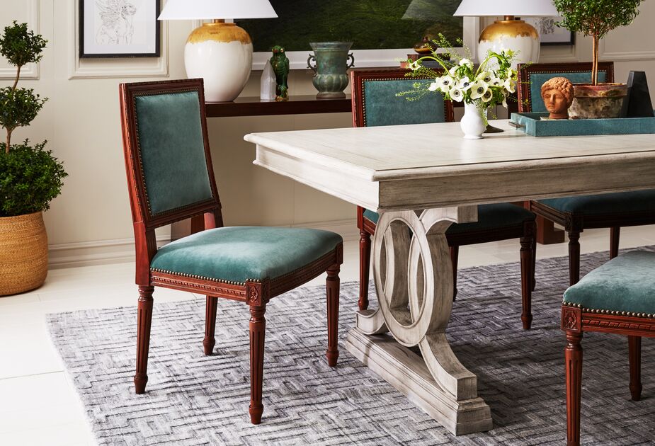 The darker colors of the Exeter Side Chairs in Jade Velvet help ground the paler tones of the dining table and rug. Find a similar rug here. 
