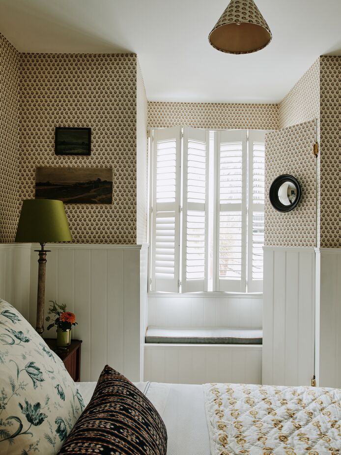 The jib door adjacent to the bedroom’s window seat opens to reveal a small closet. Sally wallpapered the door so that it blends seamlessly with the walls. 
