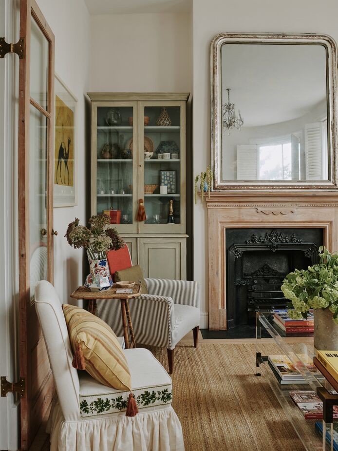 The antique painted cabinet in the living room is one of Sally’s favorite pieces. It stores glassware and dishes that don’t fit in the flat’s petite kitchen. The mirror over the mantel is another antique, but you can find a similar new version here and a similar rug here.
