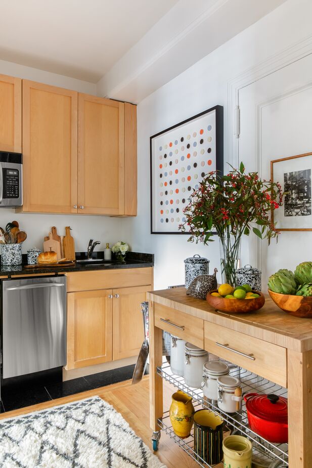 Another Dawn Wolfe artwork, Tangerine and Black Dot Collage, hangs in the kitchen. (Rainbow Square Dot Collage is a similar work.) The wheeled island makes up for the kitchen’s lack of drawers while adding always-useful counter space and open shelving.
