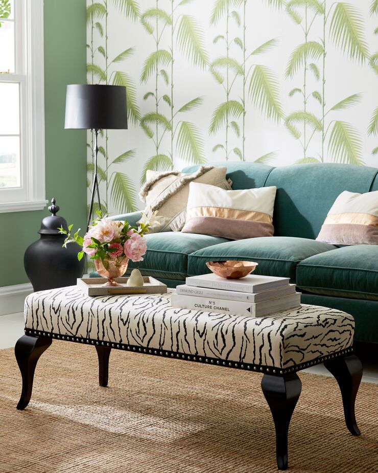 The animal print on the ottoman and the tropical wallpaper behind the Joplin Sofa in Jade freshen up the furniture’s classic silhouettes. So does using a natural-fiber rug instead of the expected Oriental rug.
