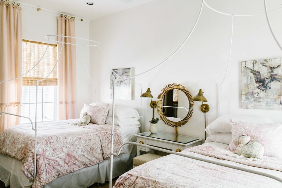 Paisley coverlets and pompoms on the sheer curtains bring out the boho leanings of the aged-brass sconces and mirror frame. Find similar sconces here.
