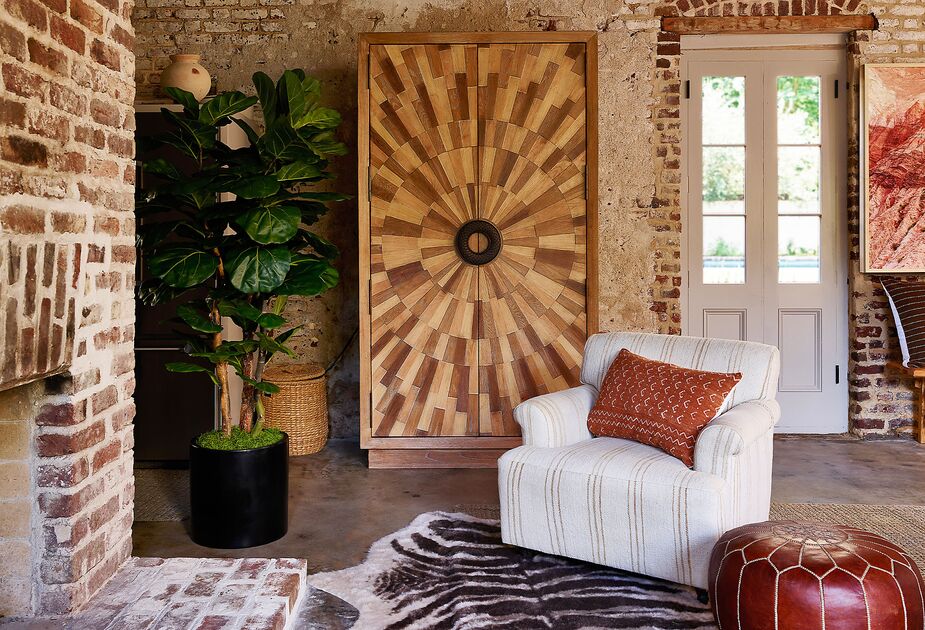 When the doors of a large cabinet are closed, you’d never know a TV rests behind them. Find a similar hair-on hide rug here and the Moroccan leather pouf here. Photo by Frank Frances.
