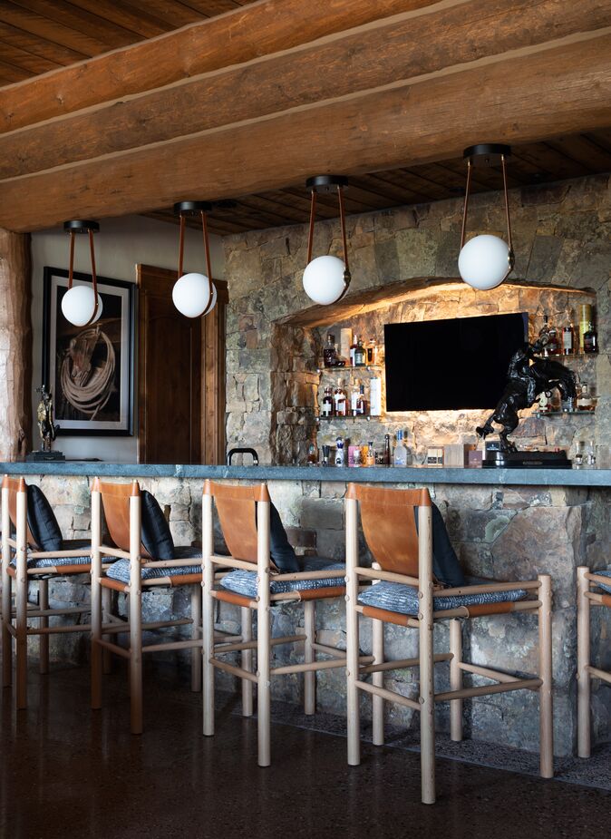 Not only do the blue cushions make the leather stools more comfortable but they also bring a softness and warmth into the downstairs bar, which is dominated by stone.
