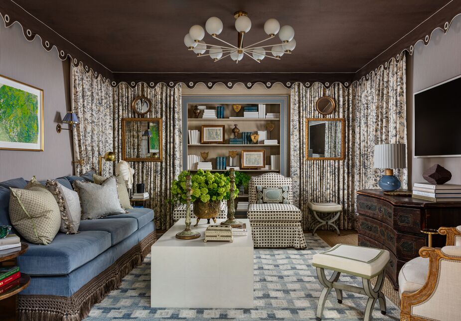 In the den/salon, Julie Dodson Webster of Dodson Interiors started with the concept of a tented ceiling, accompanied by wall-to-wall drapery. Amid the antiques and classic design elements, “modern art adds a contemporary spirit and levity to the setting to foster conversation, comfort, and nuanced layers,” Julie says. The ceiling light fixture and the geometric rug have the same effect.
