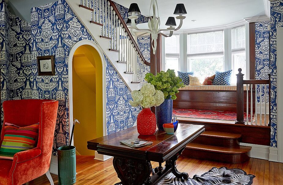 In the entryway, a bright and playful wallpaper by David Hicks gives a sense of lightness to the dark wood trestle table, a family heirloom, and the existing wood detailing.
