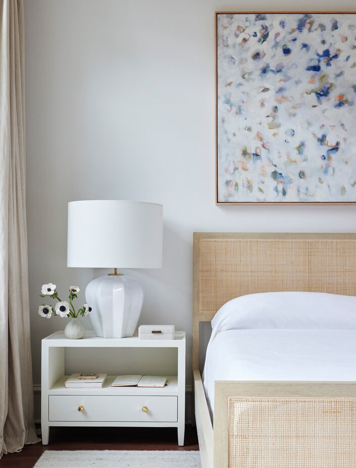 An abstract art piece, dotted with blues and grays, adds a touch of color to the serene bedroom.
