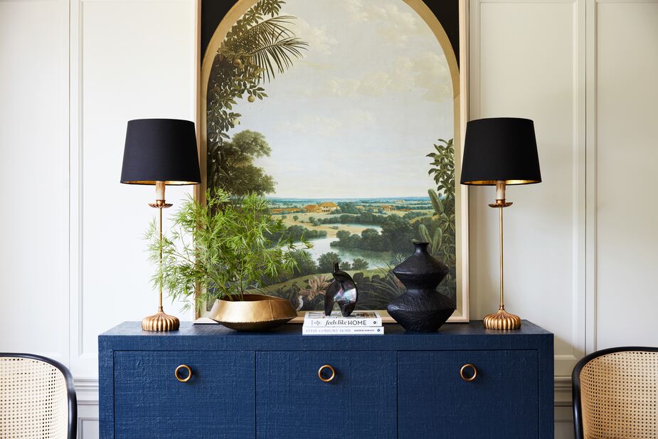Vista View from designer Olivia Song’s exclusive curation for One Kings Lane, helps unify the diverse objects that make up the vignette atop the Kos Raffia Three-Door Sideboard in Navy. The Clove Stem Buffet Lamps in Gold/Black reinforce the symmetry. Find the vase here. Photo by Joe Schmelzer.
