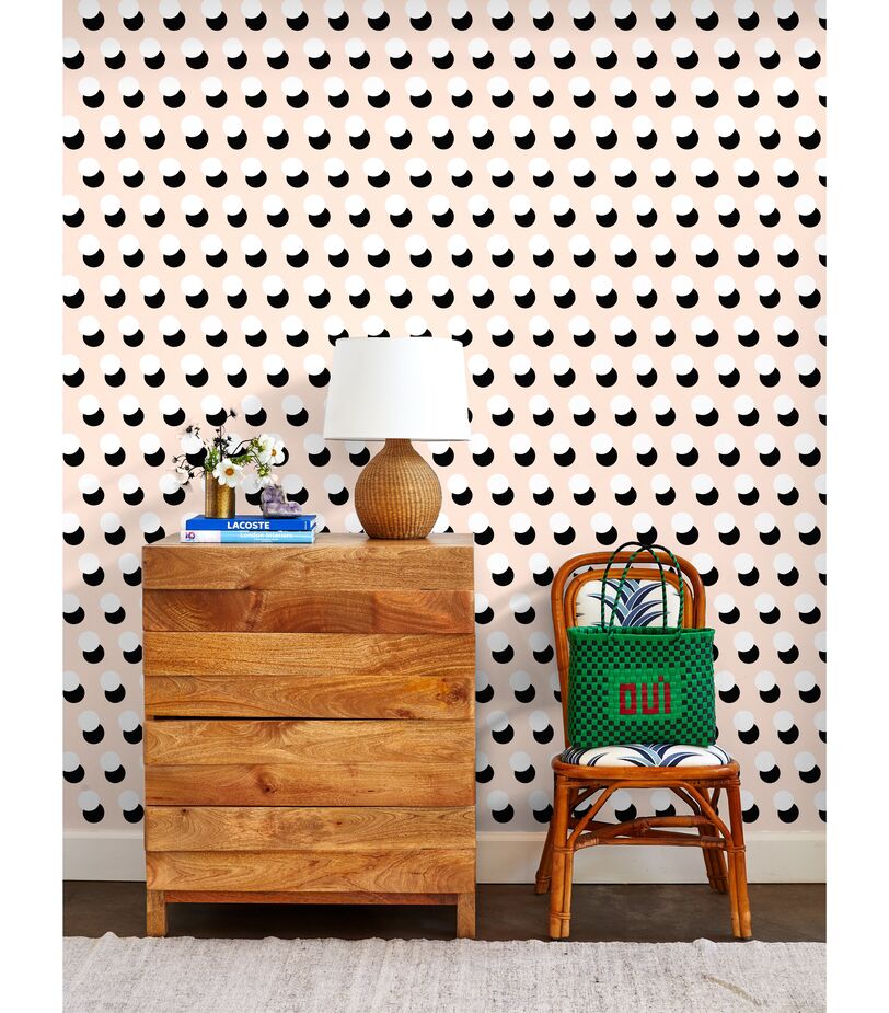 The peach background of the Clare V Pop Dots Wallpaper softens the punchiness of the mod black-and-white circles. 
