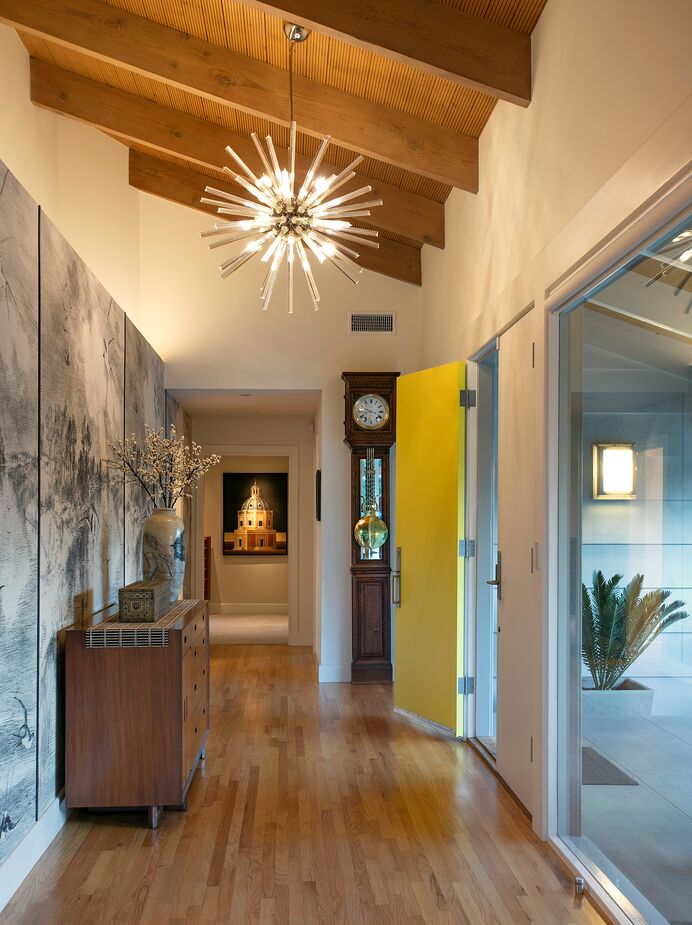 “I am most proud of how a long, awkward, nondescript entryway was transformed into a beautiful layered space with an inviting yellow front door and a secret door hidden behind the wallpaper,” Karen says. Find a similar Sputnik chandelier here. 
