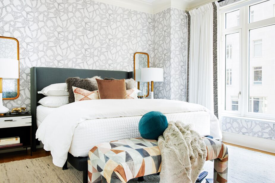 The gold-frame mirrors flanking the Kelly Wingback Bed in Charcoal help ensure that the main bedroom is as glam as the rest of the apartment. The rounded corners of the Hazel Bench mimic those of the mirrors. Find the rug here, the teal ball pillow here, and the lumbar pillows here.
