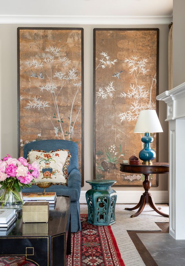 Layering a bold red antique rug atop the larger neutral floor covering helps delineate this portion of the sprawling living room. Find an identical table lamp here and a similar armchair here. 
