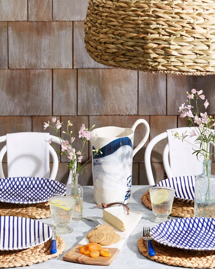 Rope place mats nod to New England’s seafaring history, as does the blue-and-white palette of the melamine dishes. Find a similar outdoor lighting pendant here.
