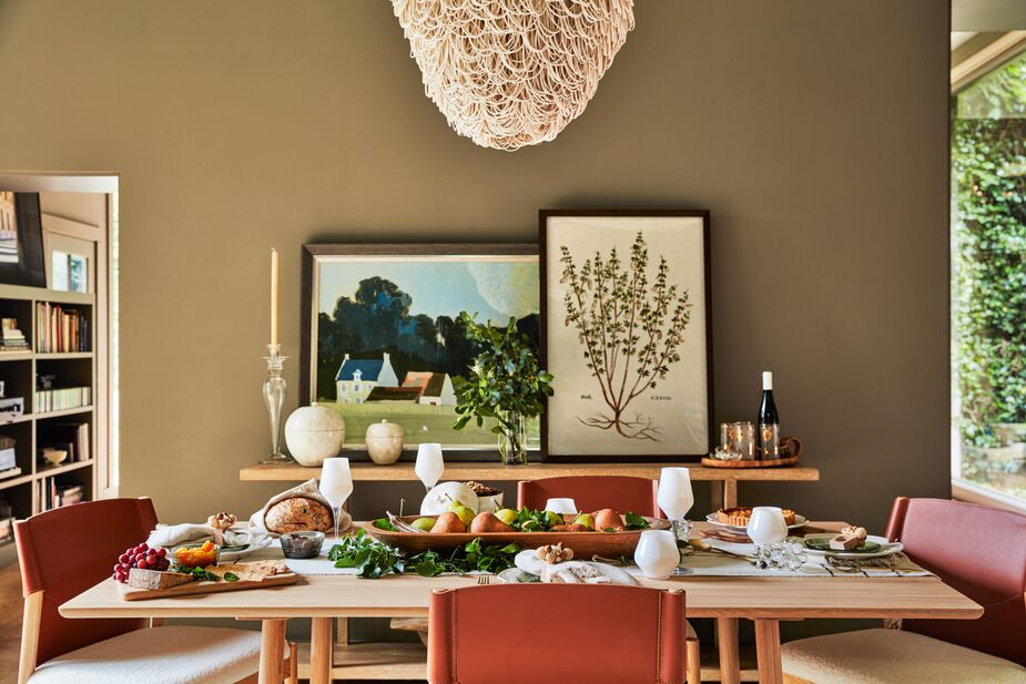 The smooth surfaces of the Profile Dining Table contrast with, and complement, the rattan loops of the Finley Chandelier and the woven Negus Table Runner. The Peyton Dining Chairs are themselves a study in contrasts, with sleek leather-blend backs and nubby faux-shearling seats. Find the white drinkware here.
