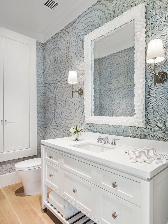 Wallpaper with a large-scale blue-and-gray floral pattern prevents this otherwise white bathroom from feeling sterile. Find similar sconces here. 
