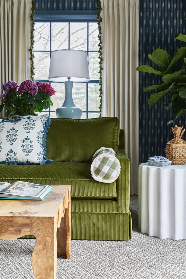 The apron and legs of the cocktail table echo the scallops of the dining area’s fixture and banquette. Fringe and tassels on the curtains and the pillows add a bespoke element thoroughly in keeping with the Palm Beach vibe. Photo by Heather Talbert. (Like the look? Then shop our Palm Beach curation.)
